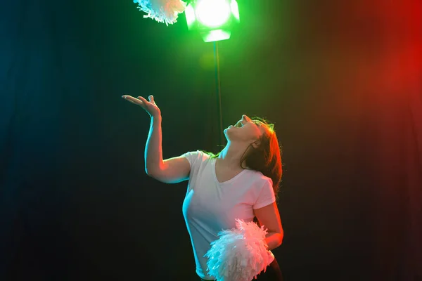 Concepto de danza, deporte y gente: una hermosa joven bailando en la oscuridad con pompones y sonriendo — Foto de Stock