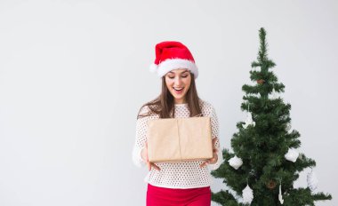 Noel, tatil ve hediyeler kavramı - santa şapka hediye kutusu beyaz arka planda tutan kadın