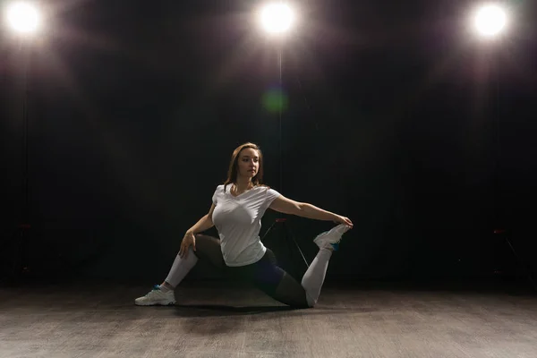 Young woman dancer gymnastics exercise pose on dark background — Stock Photo, Image