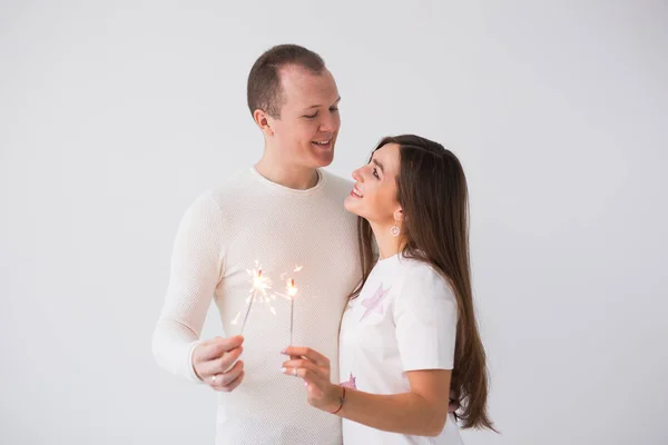 バレンタインデー コンセプト - 若い幸せな笑みを浮かべて白い背景の花火で祝う陽気な魅力的なカップル — ストック写真