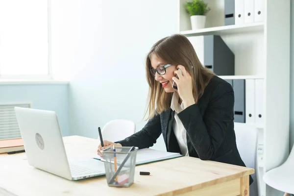 Concept d'affaires, d'agent immobilier et de personnes - Femme attrayante au bureau parlant au téléphone et prenant des notes — Photo