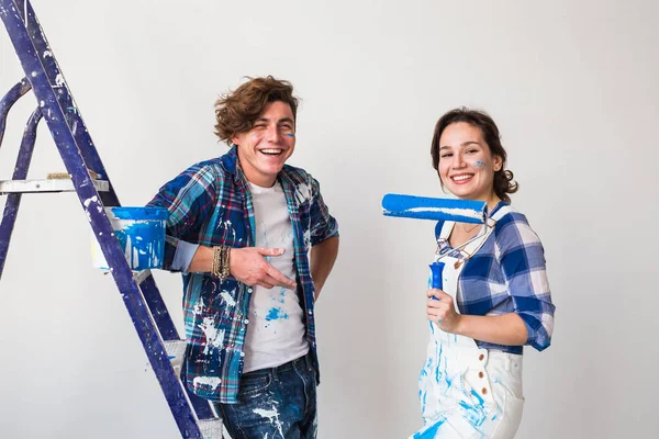 Repair, renovation and love couple concept - young family doing repair and painting walls together and laughing — Stock Photo, Image