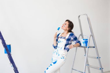 Onarım, yenileme, yeni ev ve insan kavramı - genç kadının beyaz duvardan tadilat yapması