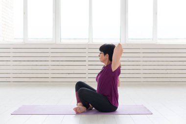 İnsanlar, yoga, spor ve sağlık kavramı - yoga üzerinde oturan çekici kadın germe ellerini izole üzerinde beyaz arka plan mat