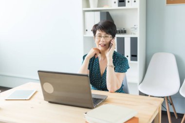 İnsanlar kavramı - ofis ve iş orta yaşlı kadın laptop ile çalışan ve bir telefon görüşmesi ofisinde