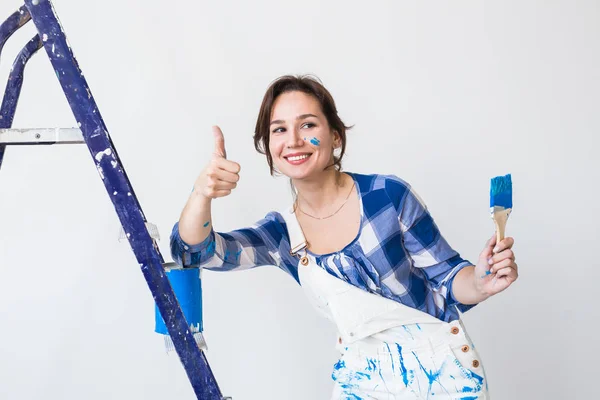 Reparación, renovación, concepto de trabajador y personas - Feliz joven pared de pintura en casa, que nos muestra los pulgares hacia arriba — Foto de Stock