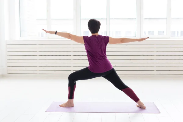 Gente, deporte y concepto de salud - Mujer de mediana edad practicando yoga, de pie en Guerrero dos ejercicios —  Fotos de Stock