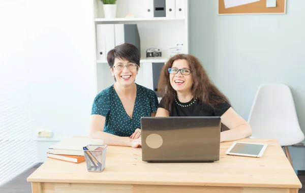 Zwei glückliche Geschäftsfrauen, die im Büro zusammenarbeiten — Stockfoto