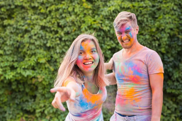 Conceito de férias, holi e pessoas - Casal feliz com pó multicolorido em seus rostos — Fotografia de Stock