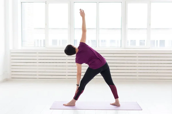 Yoga, armonía, concepto de personas - una mujer de mediana edad está practicando el yoga y mirando por la ventana —  Fotos de Stock