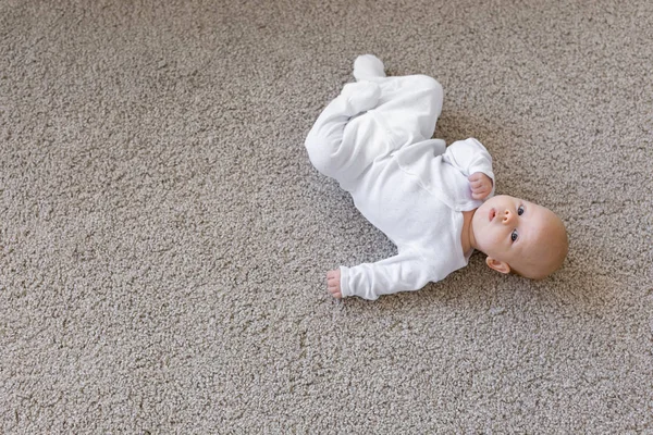 Kindheit, Säugling und Menschen Konzept - Baby liegt auf dem Rücken auf dem Boden und schaut nach oben. Hintergrund mit Kopierraum — Stockfoto