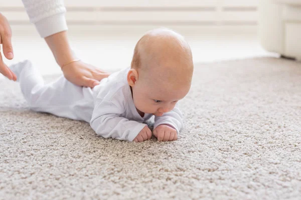 Barndom, spädbarn och personer koncept - baby flicka lära sig att krypa på golvet — Stockfoto