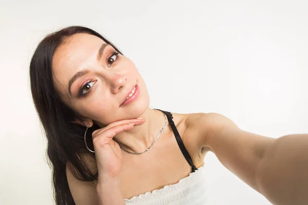 Primo piano di giovane bella donna che prende selfie su sfondo bianco — Foto Stock
