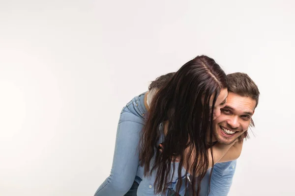 Divertimento e conceito de relacionamento - Homem carregando namorada de costas no fundo branco — Fotografia de Stock