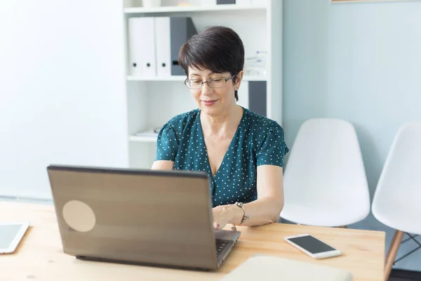 Geschäfts-, Technologie- und Personenkonzept - Frauen mittleren Alters arbeiten im Büro und nutzen einen Laptop — Stockfoto