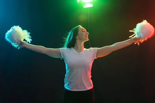 Concepto de danza, deporte y gente: una hermosa joven bailando en la oscuridad con pompones y sonriendo — Foto de Stock