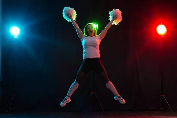 Animadora chica feliz bailando sobre fondo oscuro — Foto de Stock