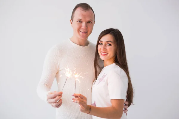 バレンタインデー コンセプト - 若い幸せな笑みを浮かべて白い背景の花火で祝う陽気な魅力的なカップル — ストック写真