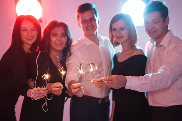 Fiesta de año nuevo, celebración y concepto de vacaciones - grupo de amigos que se divierten con los bengalas —  Fotos de Stock