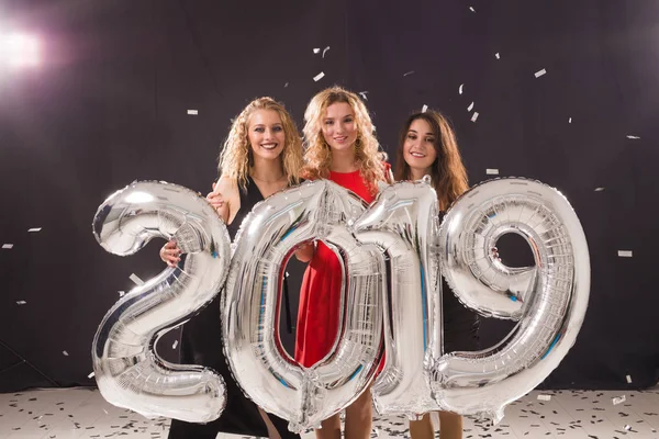 Concetto di festa di Capodanno. Gruppo di giovani donne con numeri argentati 2019 e coriandoli — Foto Stock