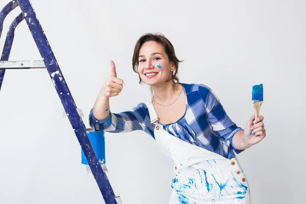Mutlu genç kadın boya duvar bize gösteren evde, tamir, tadilat, işçi ve insanlar kavramı - yaşasın — Stok fotoğraf