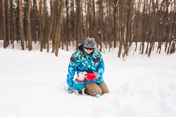Владелец домашних животных и зимняя концепция - женщина средних лет, играющая со своим Джеком Расселом терьером в снежном парке . — стоковое фото
