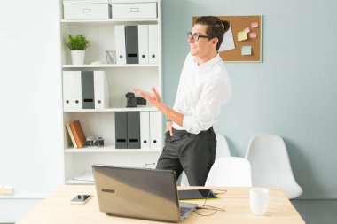 İş, ofis, insanlar kavramı - gözlük standları bir bilgisayarın yakınında ofiste yakışıklı adam ve gülümseyen