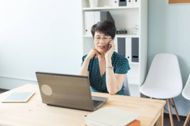 İnsanlar, teknoloji ve iletişim kavramı - yetişkin iş kadını ofiste telefonla konuşuyor