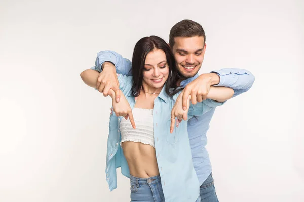 Pessoas e conceito de gesto - jovem mulher bonita e homem bonito apontando para baixo sobre fundo branco — Fotografia de Stock