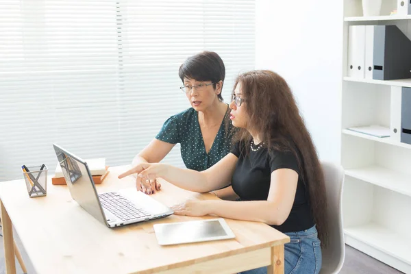 Büro, Geschäftsleute und Grafikdesign-Konzept - Frauen sitzen mit Laptop im Büro und diskutieren Ideen, schauen auf den Bildschirm, hören Meinungen — Stockfoto