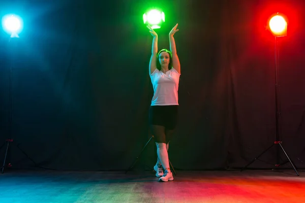 Modern Dance, Sport und People Konzept - junge Frau tanzt Jazzfunk in der Dunkelheit unter buntem Licht — Stockfoto