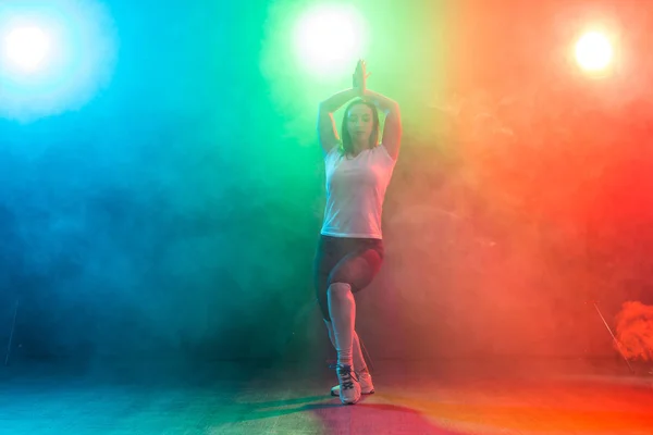 Concepto de danza moderna, deporte y gente: mujer joven bailando jazz funk en la oscuridad bajo una luz colorida — Foto de Stock