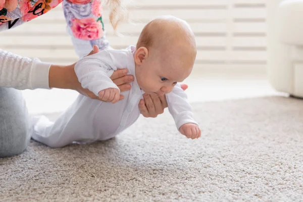 Barndom, spädbarn och personer koncept - baby flicka lära sig att krypa på golvet — Stockfoto
