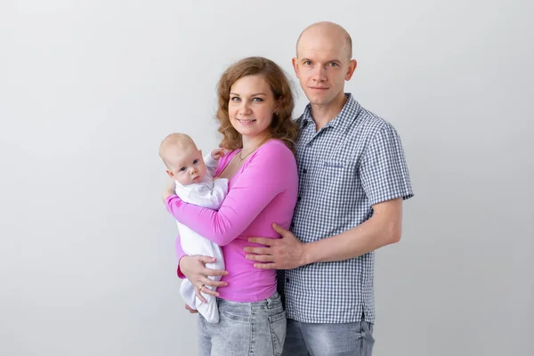 Concepto de familia, infancia y paternidad: padre, madre sosteniendo un lindo bebé sobre un fondo blanco con espacio para copiar — Foto de Stock