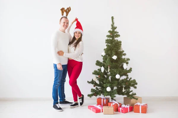 Zimowe wakacje koncepcja - Christmas Couple sobie Santa Hat i jelenie rogi. Uśmiechający się rodzinne uroczystości — Zdjęcie stockowe