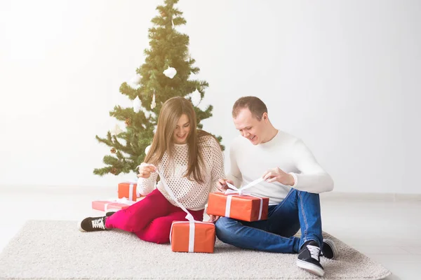 Feliz pareja joven celebrando en casa. Hombre y mujer guapos abre cajas de regalo — Foto de Stock