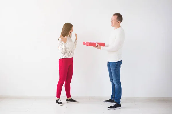 Gente, Navidad, cumpleaños, vacaciones y San Valentín concepto de día - Hombre guapo está dando a su novia una caja de regalo sobre fondo blanco —  Fotos de Stock