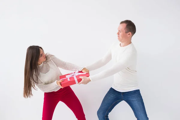 Jovem casal bonito lutando por caixa de presente sobre fundo branco . — Fotografia de Stock