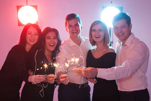 Festa de ano novo, celebração e feriados conceito - Jovens homens e mulheres alegres segurando faíscas ardentes — Fotografia de Stock