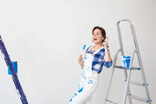 Gente, renovación y concepto de trabajo - Hermosa mujer de pie con escalera y paredes de pintura — Foto de Stock