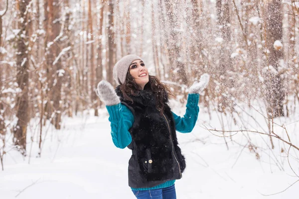 幸せな若い女が屋外の雪の森で雪で遊ぶ — ストック写真