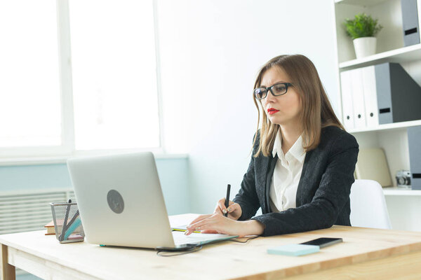 Working, business, technology and designer concept - young woman using tablet and watching in laptop