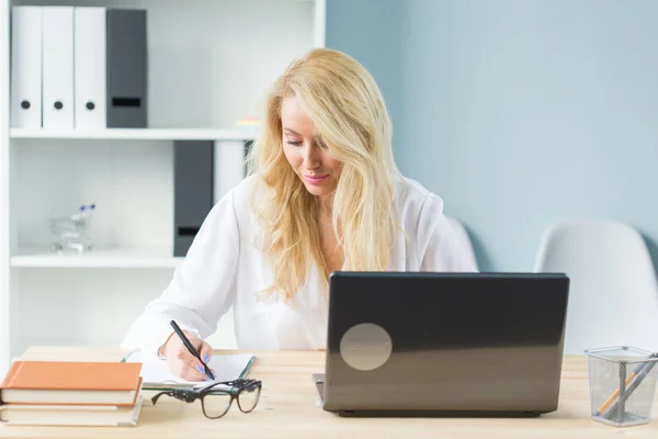 Concept technologie, travail et personnes - Belle femme blonde assise à son bureau et travaillant sur un ordinateur portable — Photo