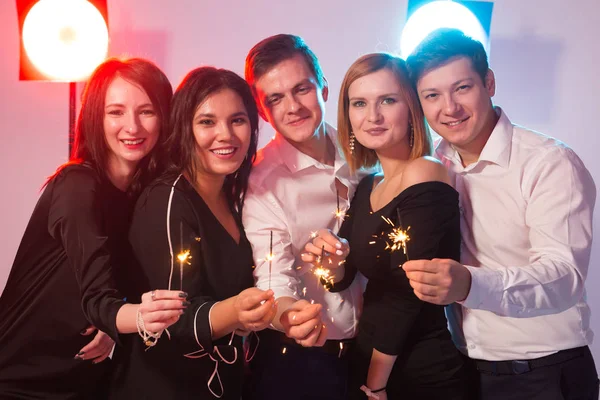 Festa de ano novo, celebração e feriados conceito - Jovens homens e mulheres alegres segurando faíscas ardentes — Fotografia de Stock