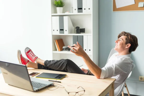 Business, humor and people concept - Handsome funny man in white shirt has a rest sitting at the table