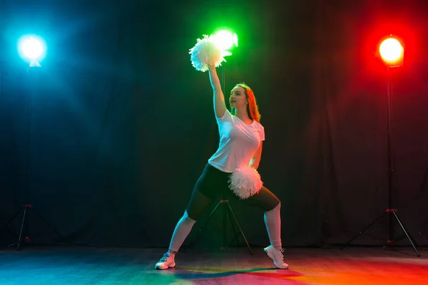 Animadora joven bailando con pompones sobre fondo colorido — Foto de Stock