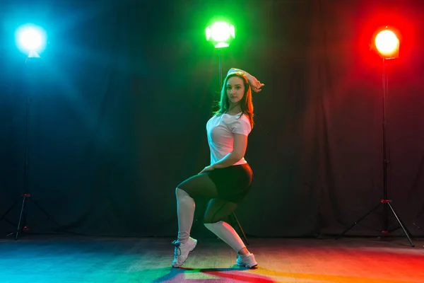 Концепция современного танца, спорта и людей - молодая женщина танцует джаз-фанк в темноте под ярким светом — стоковое фото