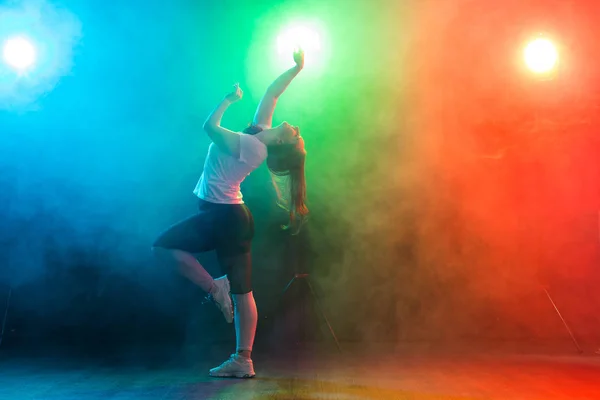 舞蹈、运动和人的概念--年轻女子在五颜六色的灯光下在黑暗中跳舞 — 图库照片