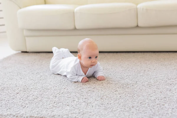 Jeugd, babyhood en mensen concept - kleine babyjongen of meisje kruipen op vloer thuis — Stockfoto