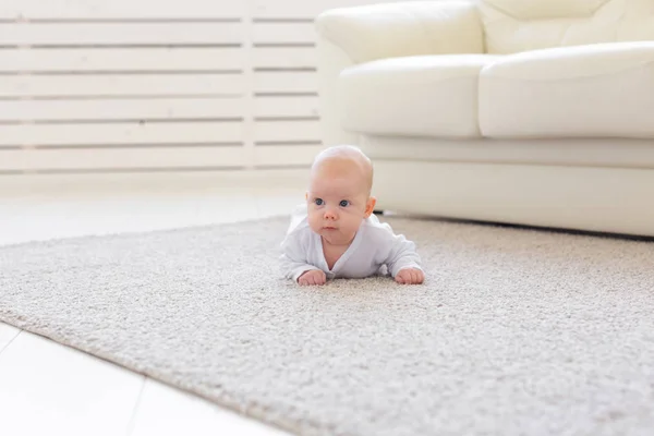 Kindheits-, Baby- und Personenkonzept - kleiner Junge oder Mädchen, die zu Hause auf dem Boden krabbeln — Stockfoto